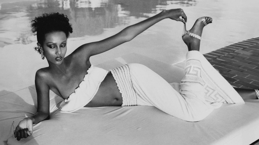 Manekenka Iman v ležečem položaju, oblečena v krilo Yves Saint Laurent. Fotografiral Kourken Pakchanian, 1977.