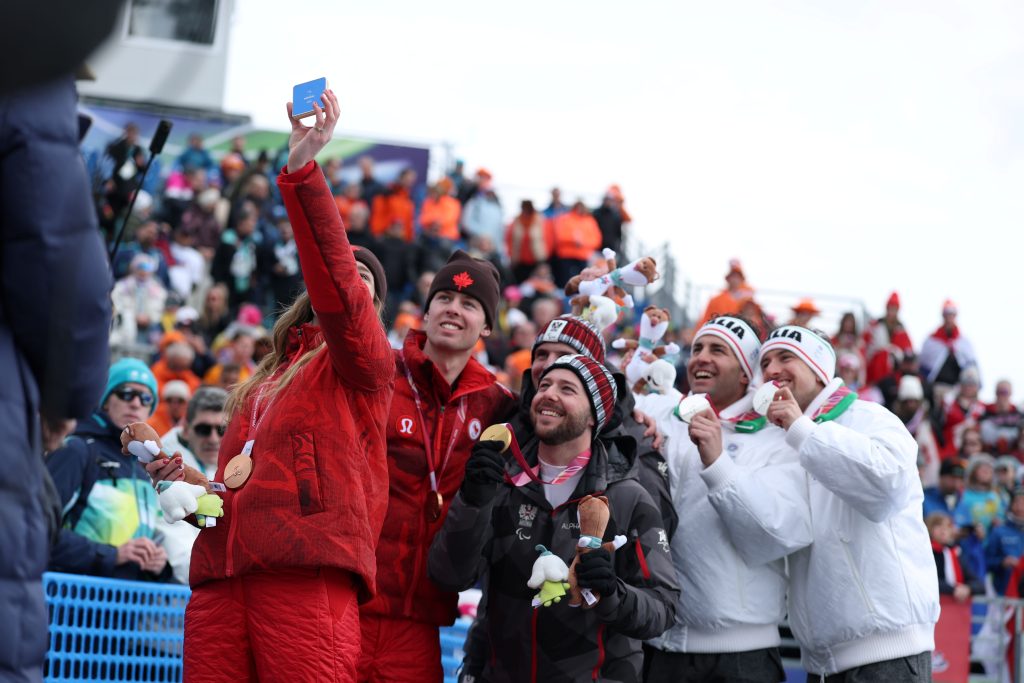 Ime fotografije: Para Alpine Skiing Super-G Vision Impaired Victory SelfieDobitnik zlate medalje Johannes Aigner iz ekipe Avstrije in njegov vodnik Nico Haberl, dobitnik srebrne medalje Giacomo Bertagnolli iz ekipe Italije in njegov vodnik Andrea Ravelli ter dobitnik bronaste medalje Kalle Ericsson iz ekipe Kanade in njegova vodnica Sierra Smith pozirajo za zmagovalni selfi, posnet z napravo Samsung Galaxy Z Flip7 Olympic Edition, med podelitvijo medalj v disciplini moški paraalpsko smučanje superveleslalom (slabovidni) tretji dan zimskih paraolimpijskih iger Milano Cortina 2026 v smučarskem centru Tofane Alpine Skiing Centre 9. marca 2026 v Cortini d’Ampezzo v Italiji.
(Foto: Linnea Rheborg/Getty Images).
